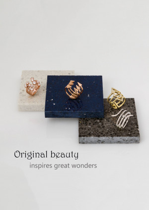 Close-up of three gold rings on textured stone platforms