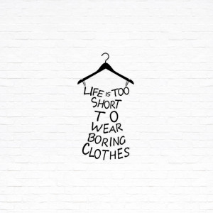 Hanger with text 'Life is too short to wear boring clothes' on a white brick wall