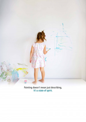 A young girl painting on a white wall with blue and colorful paint.