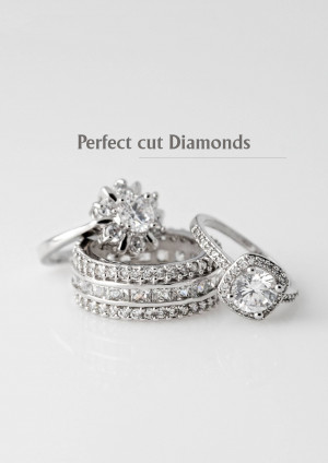 Close-up of three diamond rings on a white surface