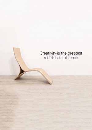 A sleek, wooden lounge chair against a white wall with the quote 'Creativity is the greatest rebellion in existence'.