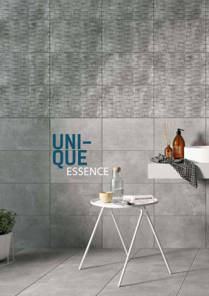 Close-up of grey textured tiles with a bathroom vignette featuring a white side table, water bottles, and soap dispenser.