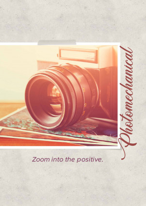 A vintage camera resting on a stack of photos with the text 'Photomechanical' and 'Zoom into the positive.'