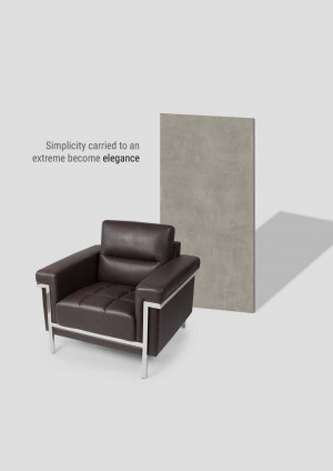 Modern brown leather armchair with silver accents against a gray wall