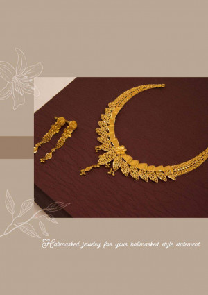 Close-up of a gold necklace and earring set on a dark wood surface