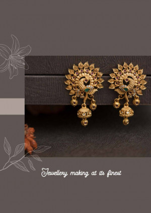 Close-up of ornate gold earrings with peacock designs and ruby accents.