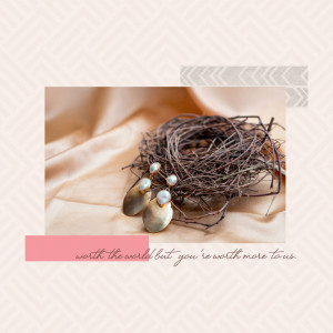 A bird's nest with pearl earrings resting on a silk cloth.