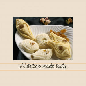 A close-up of a white plate filled with various Indian sweets like laddu and barfi, garnished with pistachios and raisins.