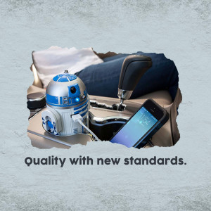 R2-D2 droid sitting in a car's cup holder with a phone and gear shift visible