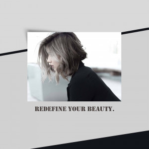 Woman looking at a laptop with text 'Redefine Your Beauty'