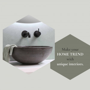 Close-up of a stylish, dark-colored bathroom sink with wall-mounted faucets and a stone bowl.