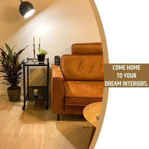 A warm and inviting living room featuring a brown leather sofa, plants, and soft lighting.