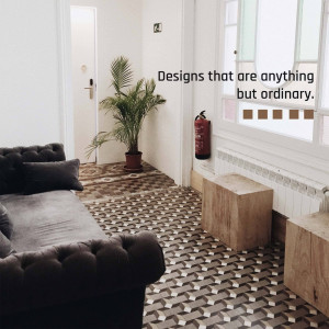 A stylish living room with a patterned floor, a potted plant, and a dark grey sofa.