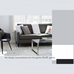 A stylish living room with a dark grey sectional sofa, white pillows, and a glass coffee table.