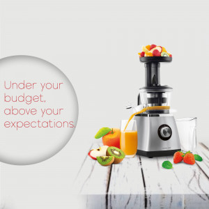 Silver juicer with fresh fruits and a glass of orange juice on a wooden surface.