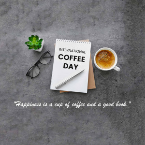 A cup of coffee, notebook, glasses, and a small plant on a grey surface with text 'International Coffee Day' and a quote.