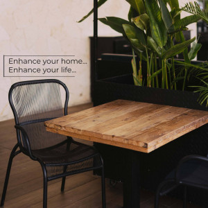 A stylish black metal chair and wooden table in a bright interior space with plants.