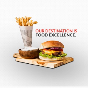 A close-up of a juicy burger with fries and dipping sauce on a wooden board.