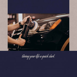 A person polishing a black car with a rotary polisher.