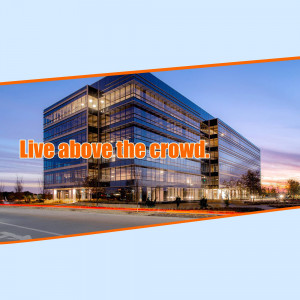 A modern glass office building with the text 'Live above the crowd'