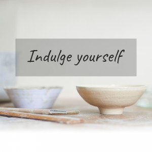 Close-up of pottery bowls and a paintbrush with the text 'Indulge yourself'
