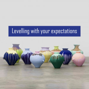 A collection of uniquely glazed pottery vases arranged on a wooden floor with a blue banner above.