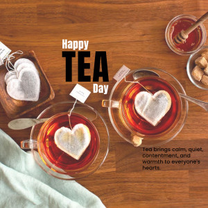 Overhead view of tea cups with heart-shaped tea bags, sugar cubes, and a jar of honey on a wooden surface.