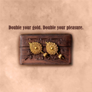 Close-up of golden earrings with floral design in a carved wooden box