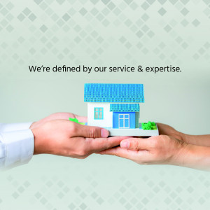 Hands holding a miniature house representing real estate service and expertise.