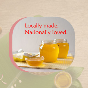 Two jars of honey with a small bowl and honeycomb on a textured surface.