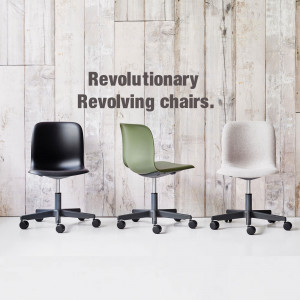 Three modern revolving office chairs in black, green, and grey against a white wooden wall.