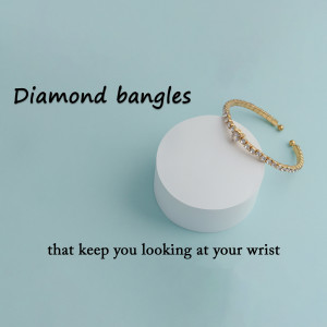 Close-up of a gold bangle with diamonds on a white surface