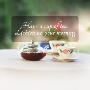 A glass teapot and a teacup with a floral design on a table with a blurred background.