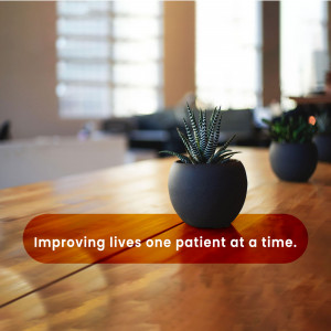 A small potted succulent plant on a wooden table with text overlay 'Improving lives one patient at a time.'