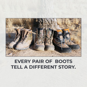 Three pairs of well-worn hiking boots resting against a tree trunk