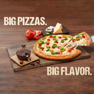 A delicious pizza with jalapeños and cheese pull, alongside a brownie and fresh ingredients.