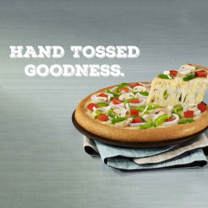A close-up of a Domino's hand-tossed pizza with vegetables.