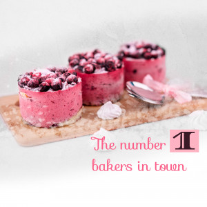 Close-up of four mini berry cheesecakes on a wooden board with a spoon and meringue