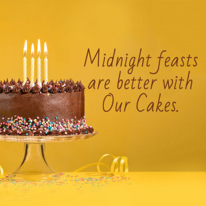 Chocolate cake with lit candles on a cake stand with sprinkles and ribbon