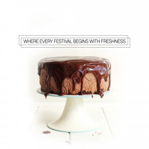 A chocolate cake with a rich chocolate drip frosting on a white cake stand.