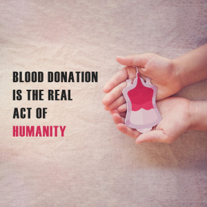 Hands holding a paper blood drop with the text 'Blood Donation is the real act of humanity'