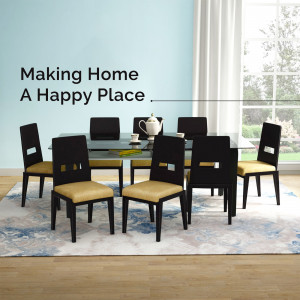 A modern dining room set with a glass table and black chairs with beige cushions.