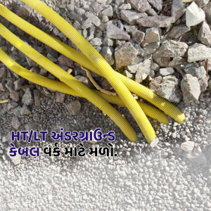 Yellow electrical cables lying on a bed of grey gravel with text 'HT/LT and 33/11 KV cable work in progress'