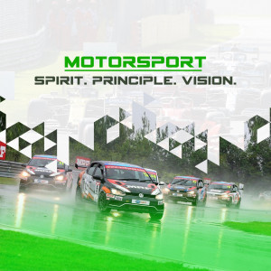 Race cars competing on a wet track with the Motorsport logo