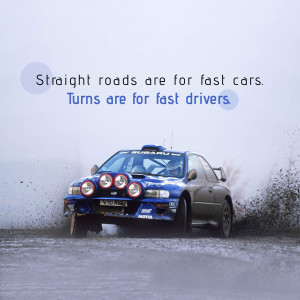 Blue Subaru Impreza rally car drifting on a gravel road with dust and spray.