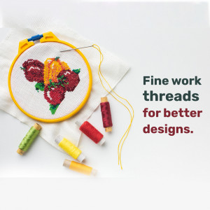 Close-up of a cross-stitch embroidery hoop featuring a colorful fruit design with threads and tools.