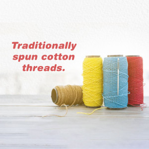 Four spools of colorful cotton thread - yellow, blue, red, and tan.