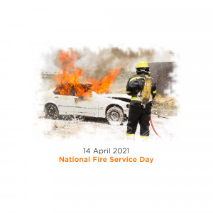 A firefighter spraying water on a burning car during National Fire Service Day.