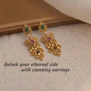 Close-up of ornate gold earrings with ruby and emerald accents