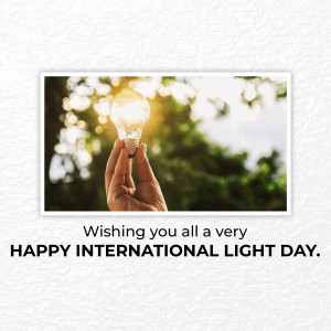 Hand holding a glowing light bulb with text wishing a Happy International Light Day